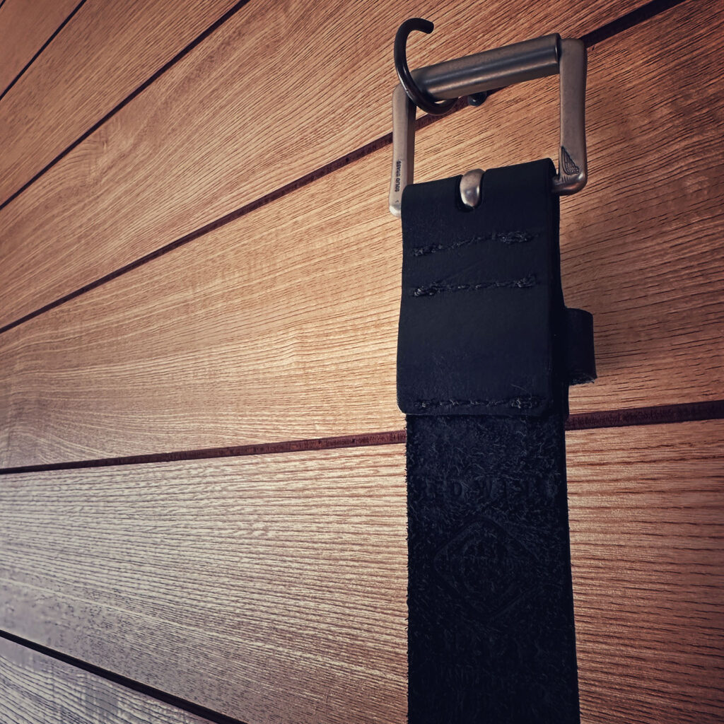 壁に吊るされたREDWING黒レザーベルト。革が少しずつ馴染んできた雰囲気がわかる写真。