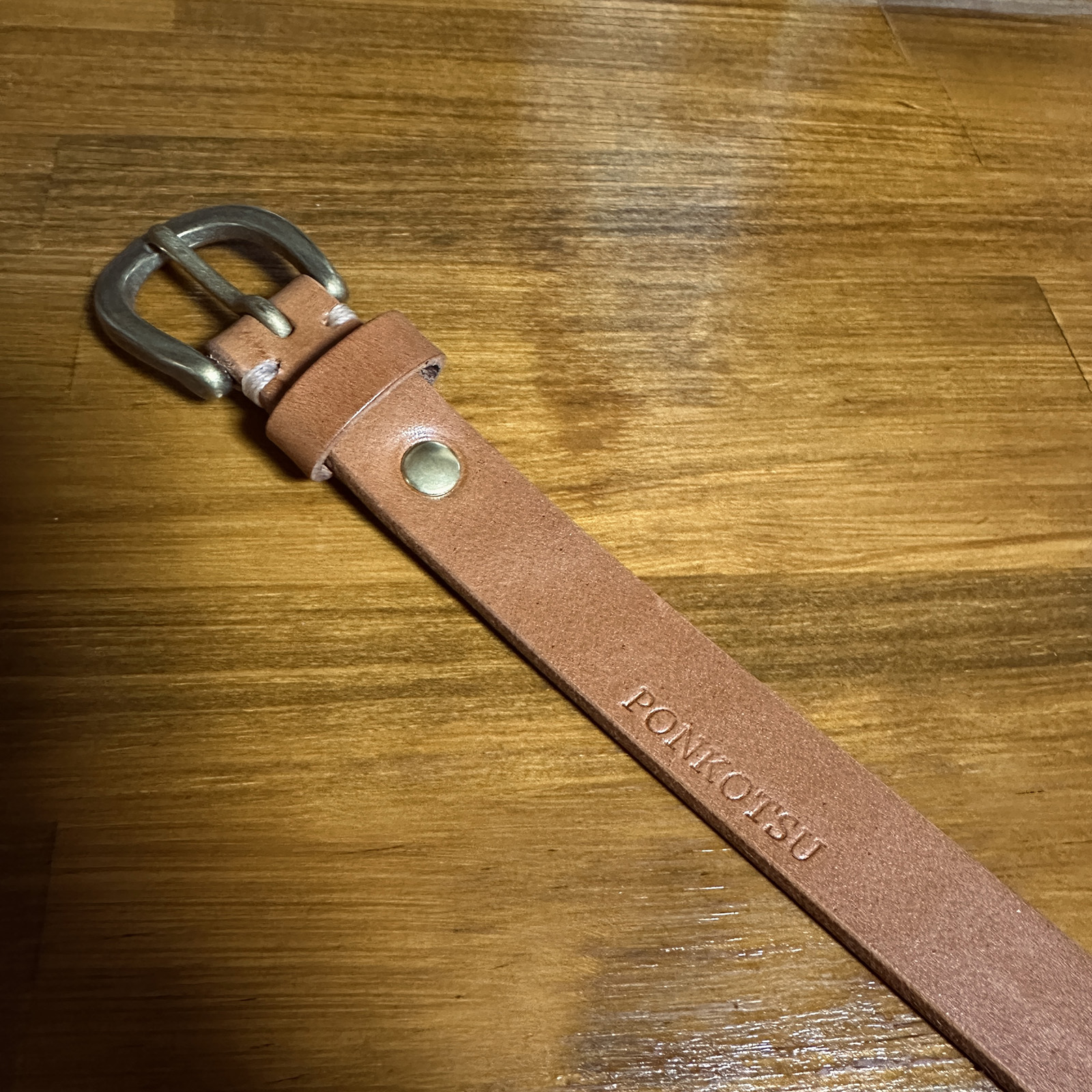 栃木レザーの細めベルト。真鍮バックルとナチュラルカラーの革、先端には「PONKOTSU」の焼印が入っている