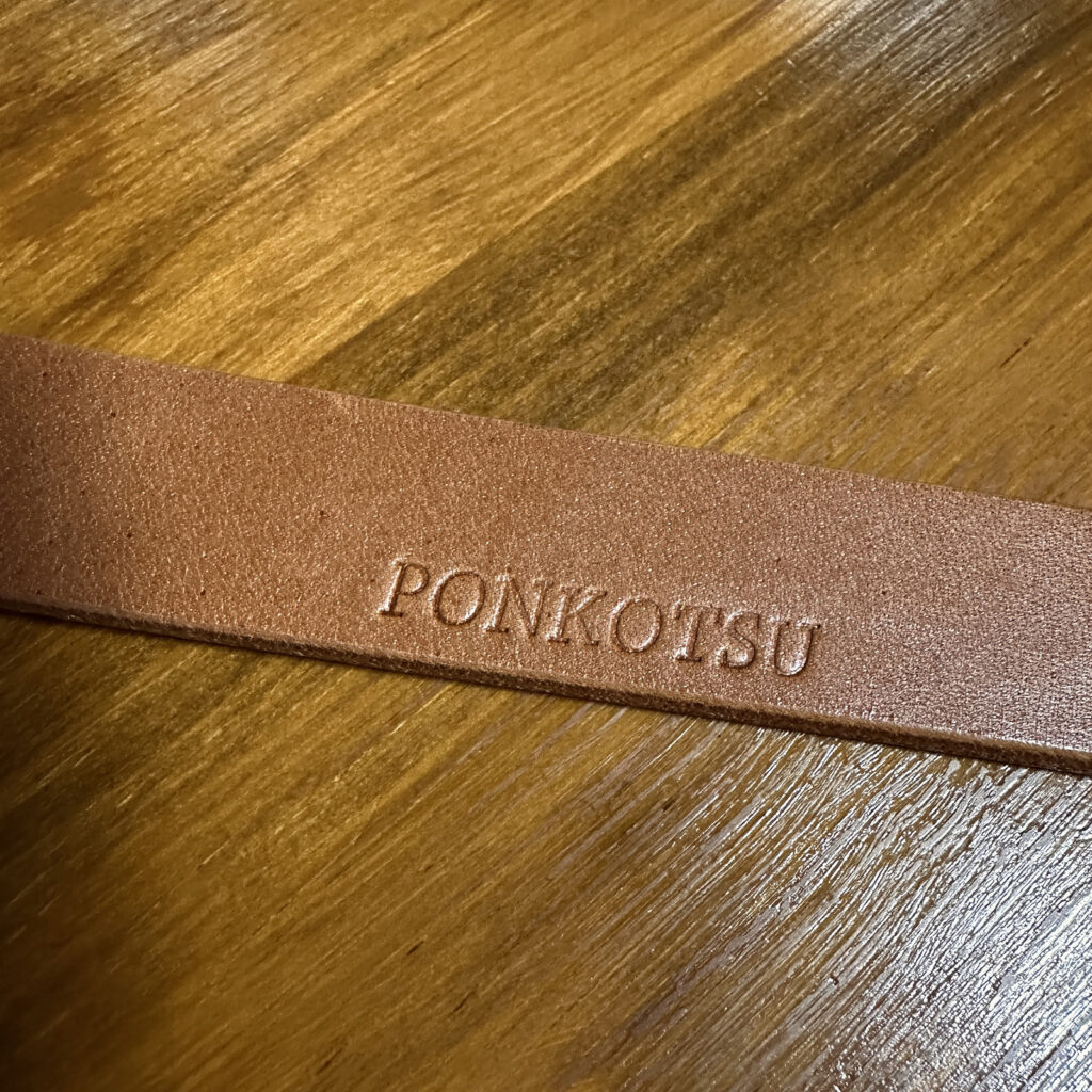 栃木レザーのベルト先端に刻印された「PONKOTSU」の焼印。新品の革の質感が分かるアップ写真