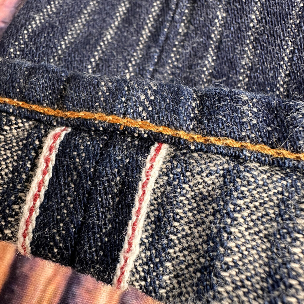 graphzeroのヘリンボーンデニム。裾のチェーンステッチと赤耳、オレンジステッチが映える12oz生地のアップ